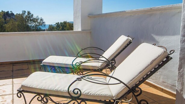 Une terrasse sur le toit avec deux chaises longues et une structure en forme de tour blanche.