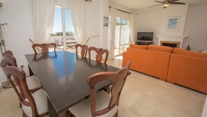 Un espace repas comprenant une table et des chaises, un canapé, un téléviseur et une cheminée.
