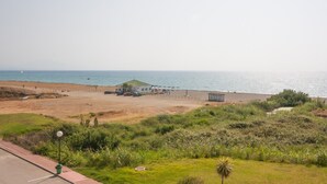 Une plage avec un petit bâtiment, des parasols et quelques personnes.