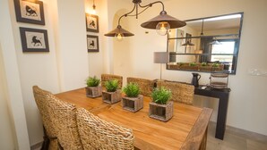 A dining area with a wooden table, wicker chairs, and potted plants. - Coto Real Andros 201 (Manilva)