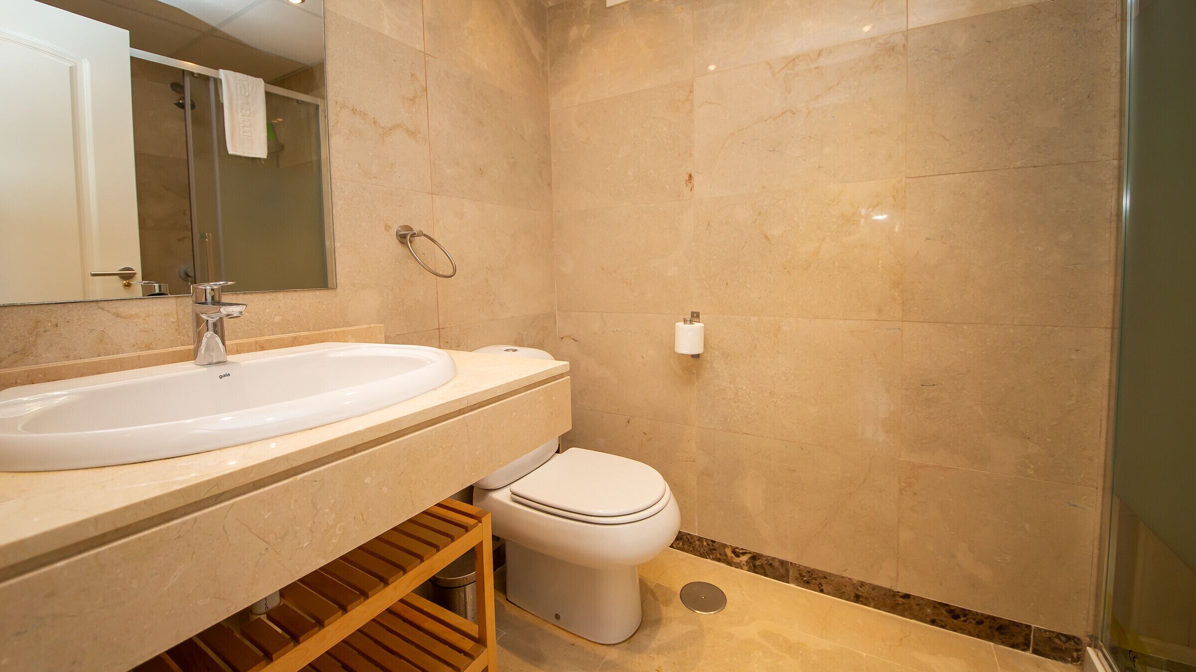 A bathroom with a sink, mirror, toilet, and shower.