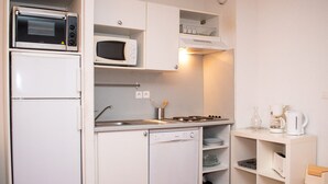 Une cuisine compacte équipée d’un réfrigérateur, d’un four à micro-ondes, d’une cuisinière et d’un lave-vaisselle.