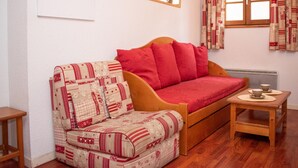 Une pièce chaleureuse avec un lit en bois, une petite table avec des tasses et une fenêtre avec des rideaux.