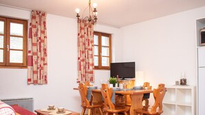 Un coin repas chaleureux, avec des meubles en bois, un téléviseur et une fenêtre agrémentée de rideaux.