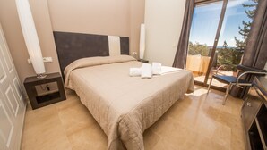 A hotel room with a bed, a nightstand, a desk, and a view of the outdoors. - Coto Real 102 Khios. (Manilva)