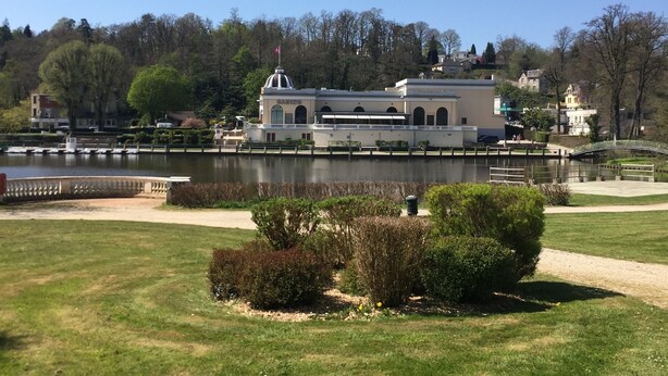Un parque con un lago, un edificio con cúpula y un puente.