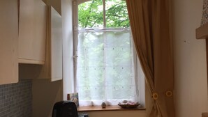 Una cocina compacta con estufa, cafetera y una ventana con cortinas.