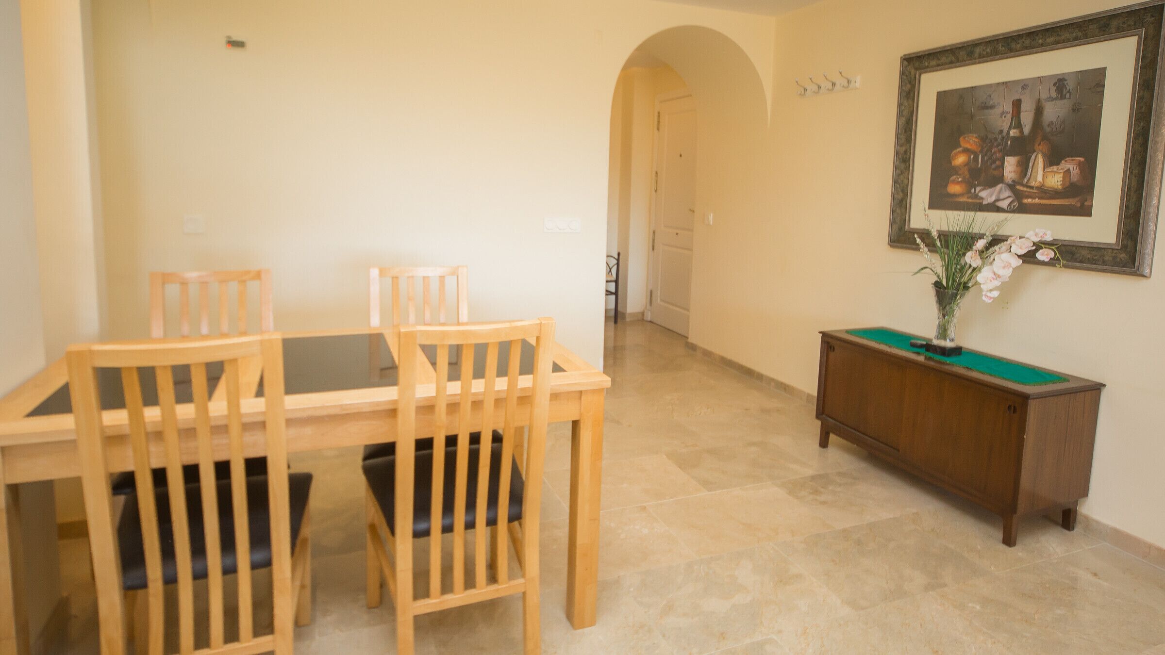 Un coin repas avec une table et des chaises en bois, un billard vert et un tableau encadré accroché au mur.