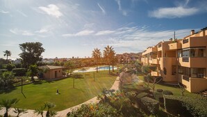 Zona residenziale con piscina, prati curati e palme.