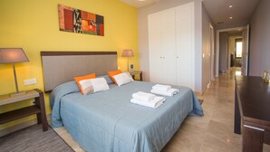 Quarto de hotel com cama, duas mesas de cabeceira, abajur, pintura e porta.