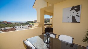 Varanda com mesa e cadeiras, vista do campo e um quadro na parede.