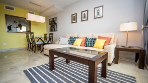 Uma sala de estar com sofá, mesa de centro, espaço de refeições e obras de arte na parede.