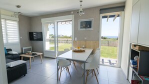 A modern kitchen with a dining area, large windows, and a view of the outdoors.