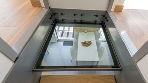 A modern room with a glass ceiling, a white table with a decorative item, and a wooden bench.