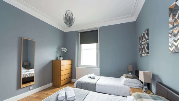 Een moderne slaapkamer met twee bedden, een kaptafel, een spiegel en een raam.