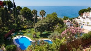 A pool surrounded by lush greenery and a view of the sea. - Spacious and bright penthouse with panorama seaview (Nerja)