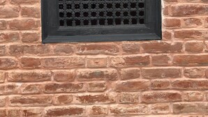 Una ventana con una celosía decorativa en un muro de ladrillo.