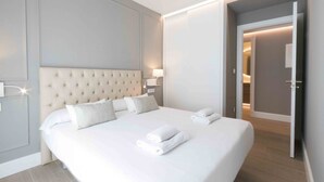 A modern hotel room with a large bed, bedside lamps, and a neatly made bed with towels.