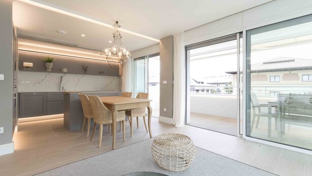 A modern kitchen with a dining area, large sliding glass doors, and a view of the outside.
