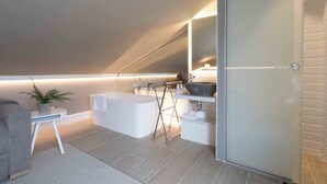 A modern bathroom with a freestanding bathtub, a large mirror, and a sink with a vessel basin.