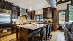 A spacious kitchen with dark wood cabinets, stainless steel appliances, and a large island with bar stools.