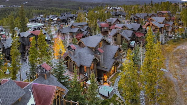 A resort with multiple wooden buildings, a ski lift, and a mountain backdrop.