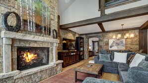 A spacious living room with a stone fireplace, a large sectional sofa, and a television.