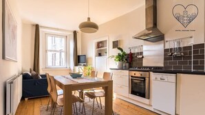 A compact kitchen with a dining area, a TV, and a potted plant. - Lovely central Edinburgh apartment (Edinburgh)
