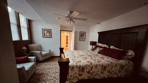 Un dormitorio con cama, una silla, una mesita de noche y un ventilador de techo.