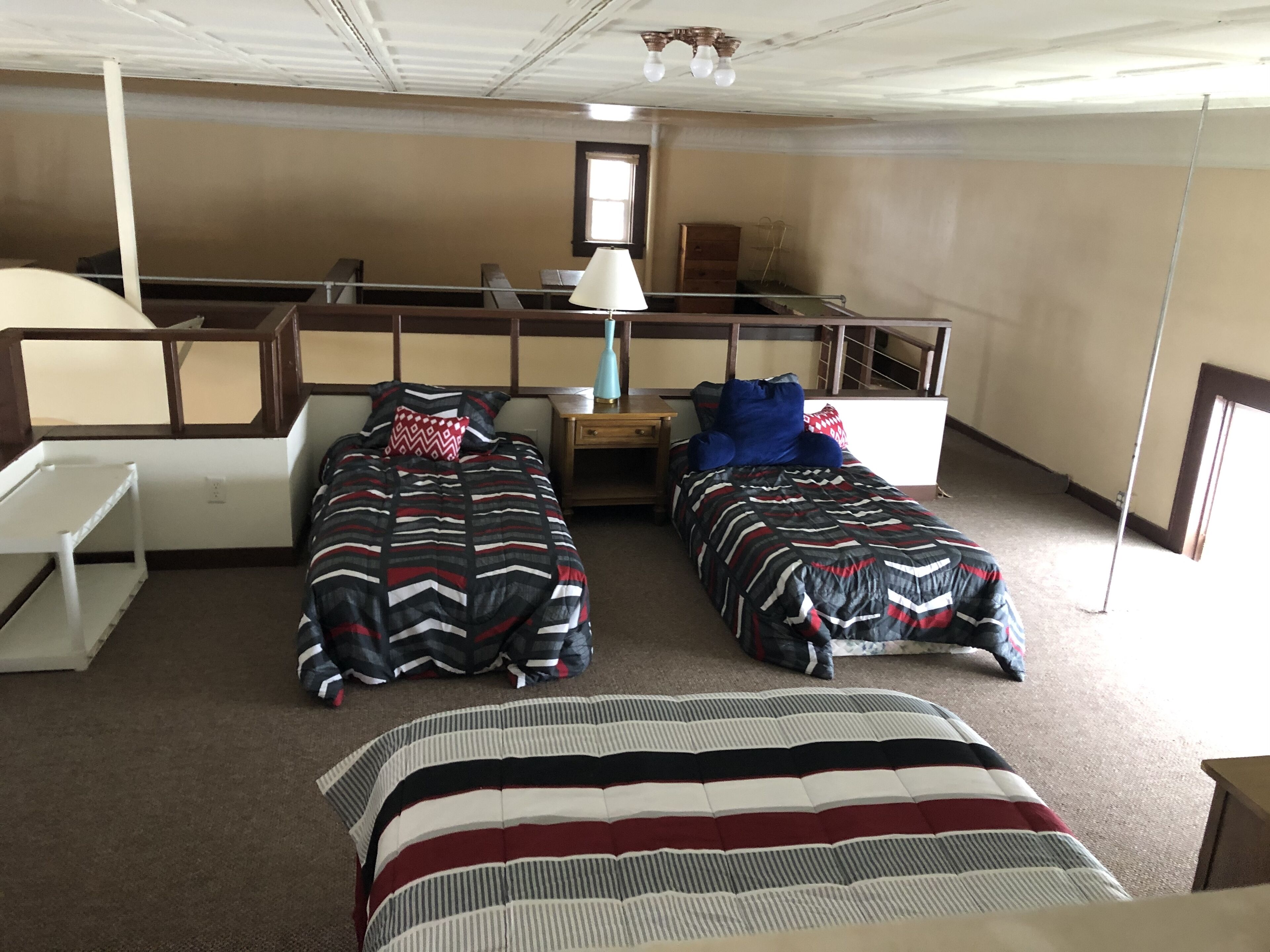 A room with two beds, a desk, a lamp, and a window.