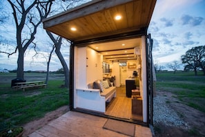 A cozy, open-plan cabin with a wooden exterior, a built-in seating area, and a kitchen.