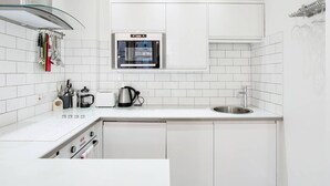 Ett modernt kök med vita skåp, en inbyggd ugn, en kaffebryggare och en diskho.