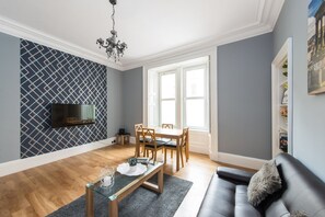 Relax in this stylish living room with a dining area, comfortable sofa, and flat-screen TV.