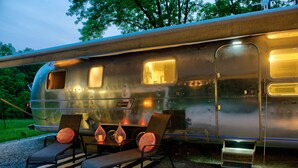 A vintage camper with a small seating area, including two chairs and a bench, and a small table with candles.