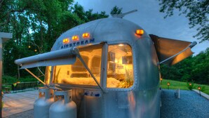 A vintage-style RV with a kitchen area, two propane tanks, and a canopy.