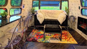 A room with a central bed, large windows, and a colorful rug.