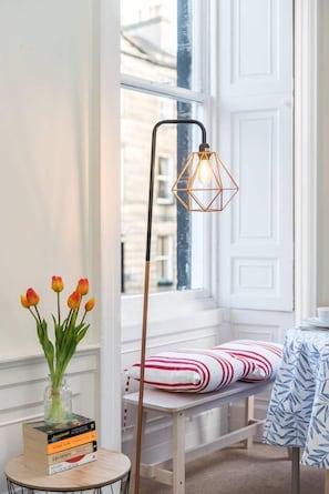 Relax in this serene space with a view, featuring a comfortable bench and a stylish floor lamp.
