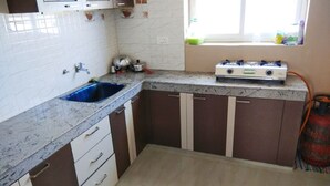 Une cuisine avec un évier bleu, des placards blancs, une cuisinière à gaz et une fenêtre donnant sur un beau paysage.