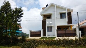 Une maison à deux étages au design moderne, dotée d’un toit plat, de grandes fenêtres et d’une entrée sécurisée par un portail.