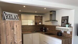 Una cocina moderna con detalles de madera, estufa integrada y una estación de café.