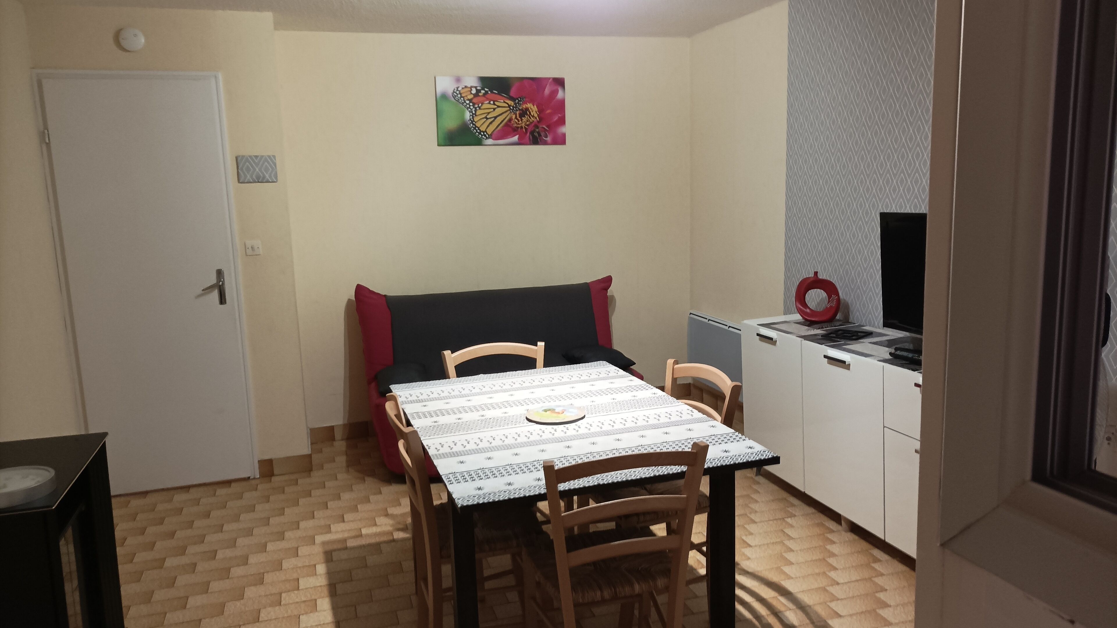 Un petit coin repas comprenant une table, des chaises, un canapé et un téléviseur.