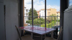 Un balcón con mesa y sillas, con vistas a una zona residencial con edificios y árboles.