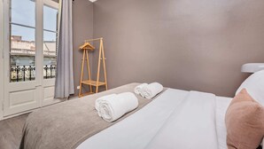 Ein Hotelzimmer mit einem Bett, einem Wäscheständer aus Holz und einem Fenster mit Vorhängen.