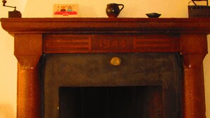 A fireplace with three green candles, a vintage sign, and a small decorative item on the mantel. - Apartment "La casa dei nonni" (Acqualagna)