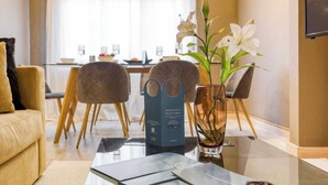 Un salon moderne avec une table basse en verre, un canapé et un coin repas comprenant des chaises et une table.