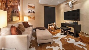 Ein modernes Wohnzimmer mit einer Couch, einem Hocker und einem an der Wand befestigten Fernseher.