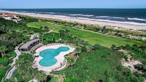 Vista aérea de un complejo turístico con piscina, playa y océano.