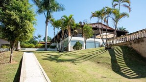 Uma área gramada bem cuidada com um caminho de concreto que leva a um edifício com telhado vermelho e antenas parabólicas.
