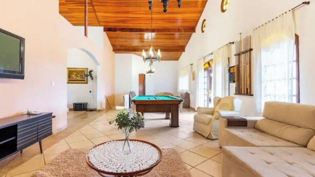 Uma sala de estar espaçosa com mesa de bilhar, sofá e televisão.