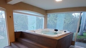 Uma área de spa com hidromassagem, escadas de madeira e janelas amplas.